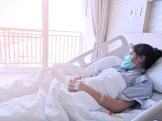 Obraz premium Asian women are sick and are hospitalized. The patient is sitting in the bed waiting to receive treatment from the doctor in the room.
