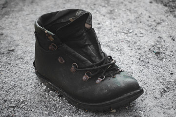 A black and white image of an old worn pair of shoes on a concrete floor