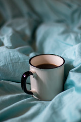 Coffee cup on a bed. Atmospheric hygge style. Good morning still life