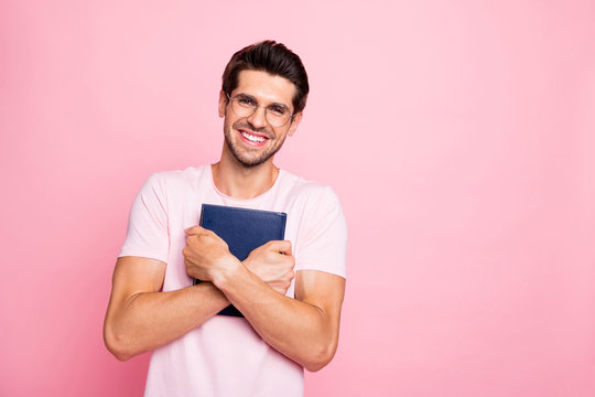 Portrait of his he nice attractive lovely peaceful cheerful cheery glad intelligent guy holding in hands hugging book library isolated over pink pastel background