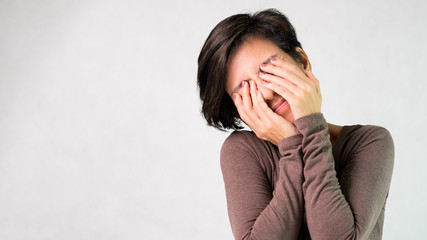 Studio portrait of an attractive middle aged asian woman hands covering eyes, gesturing of don't want to see. Social network, Dangers, Information age, Computer vision syndrome, See no evil concept.