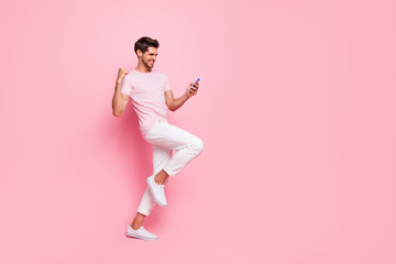Fototapeta na wymiar Full length body size view portrait of his he nice attractive cheerful cheery guy reading good news notification rejoicing isolated over pink pastel background