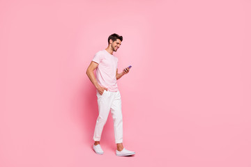 Fototapeta na wymiar Full length body size view portrait of his he nice attractive content cheerful cheery guy walking enjoying free spare time isolated over pink pastel background