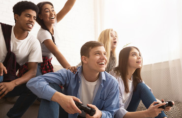 Teen friends playing video games at home © Prostock-studio