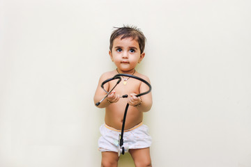 Little cute girl with stethoscope sitting on carpet