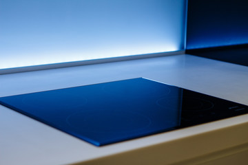 Frying pan on modern black induction stove, cooker, hob or built in cooktop with ceramic top in white kitchen interior