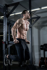 Shirtless muscular man doing dips exercise at the gym