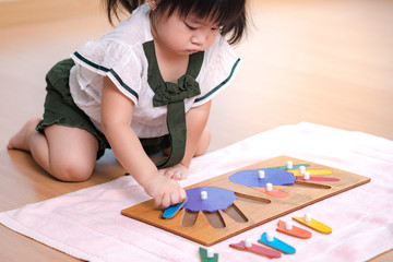 An adorable asian preschool little girl (2-3 years) in Montessori classroom engaged sensory wooden puzzle activity. 10 fingers, Fine motor skills, Montessori method, Child development, Early education