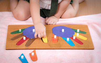 Closeup: Hands of a preschool little girl 2-3 years in Montessori classroom engaged sensory wooden...