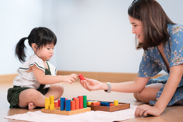 A precious moment of adorable little asian preschool girl 2 years old, learn by play wooden colorful blocks with her beautiful mother. Early education, Montessori at home, Child development concept.