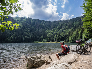 Mountain biker resting at lake Feldsee near Mt Feldberg, Baden-Württemberg, Germany