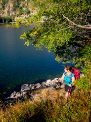 Women hiker passing by lakeside at Lac Blanc, France