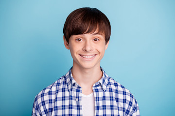 Portrait of charming boy looking wearing checked shirt isolated over blue background