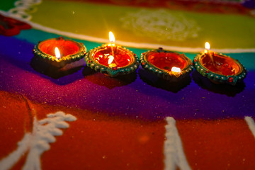 celebration of Indian festival Diwali - oil lamps lit on colorful rangoli