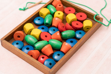 Top view closeup of colorful wooden beads, needle in the tray. Educational toys, Montessori sensorial activity for toddlers and baby, Hands eyes coordination, Cognitive skills, Children development.