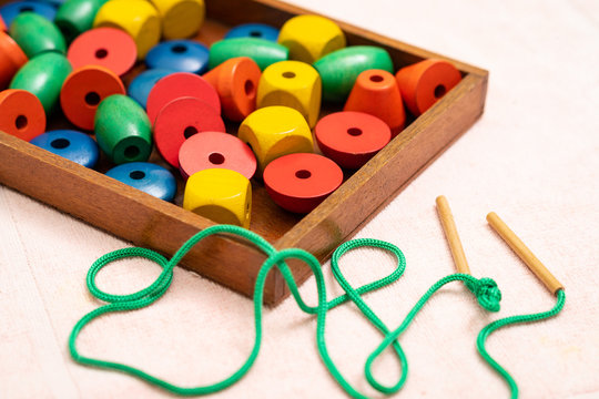 Top view closeup of colorful wooden beads, needle in the tray. Educational toys, Montessori sensorial activity for toddlers and baby, Hands eyes coordination, Cognitive skills, Children development.