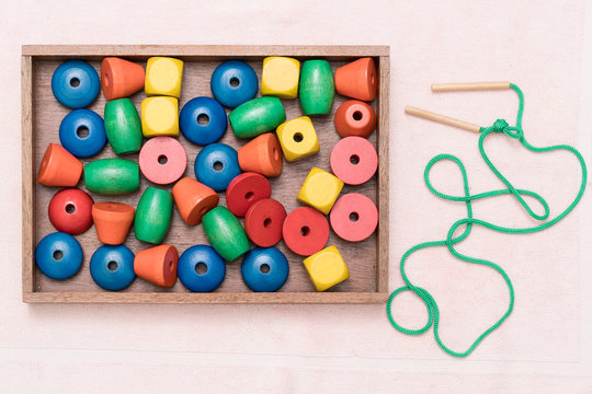 Top view closeup of colorful wooden beads, needle in the tray. Educational toys, Montessori sensorial activity for toddlers and baby, Hands eyes coordination, Cognitive skills, Children development.