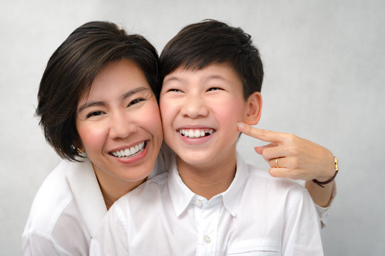 A happy face of asian smart looking preteen boy and mom laughing together. Deciduous teeth, Milk teeth, Healthy and strong, Dental oral care, Bonding, Mother and son, Studio portrait white background.