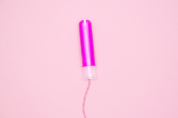 one cotton tampon with purple applicartor on pink background. Menstrual cycle period concept. Woman days hygiene protection. Top view, flat lay - obrazy, fototapety, plakaty