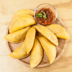 Tasty colombian food, fried empanada; photo on wooden background.
