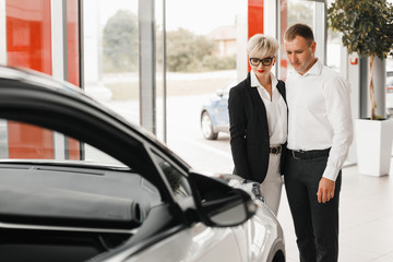 Couple buying the car. Pair in a car salon сhoose car