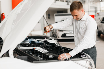 man checks the presence of oil in the car close-up