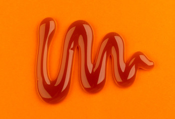 Caramel sauce on orange color background, top view