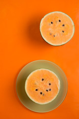 halfs of fresh ripe orange watermelon around orange background