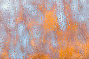 Raindrops on the window and orange autumn leaves outside