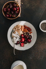 Healthy summer vegetarian breakfast with granola, cherry, pecans, coconut flakes, chia and oat milk. Flat lay, top view.