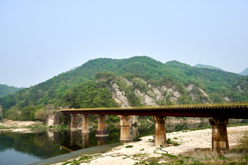 Fototapeta na wymiar A view of an old railroad bridge and its reflection upon the Seom river at Wonju, South Korea.