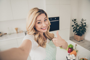Self-portrait of her she nice attractive lovely sweet charming cute cheerful cheery content wavy-haired lady showing thumbup in light white interior kitchen indoors