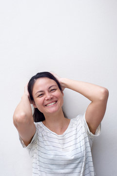 cheerful asian girl with hands behind head against white background