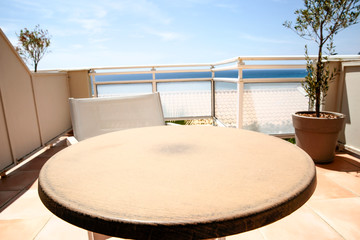 Table background on a beautiful blue sky and ocean view. Empty space on a round wooden table top for an advertising product.