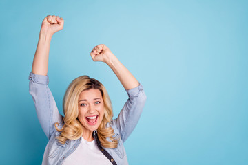 Fototapeta premium Portrait of cheerful person raising fists shouting yeah isolated over blue background