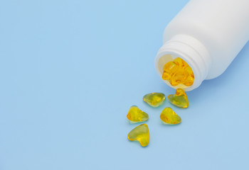 Medicine concept. White bottle of medicine and vitamin Ze-oil on a blue background, vitamin pouring out from bottle, Front view photo.