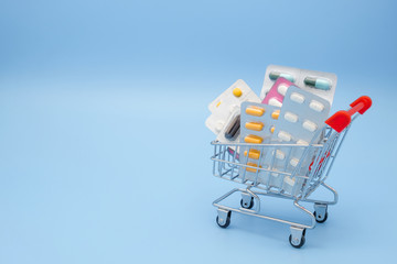 Medicine concept. Various capsules, tablets and medicine in shop trolley on a blue background. Pills concept. Buy and shopping medicine.