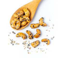 Sesame Coated Cashew Nuts on wooden spoon. Isolated on white background