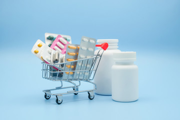 Medicine concept. Various capsules, pack of medicines in shop trolley with medicine bottle on a blue background. Pills concept. Buy and shopping medicine.