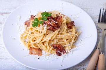 Pasta carbonara with bacon, cheese Parmesan and parsley. Traditional Italian dish. Close-up, selective focus.