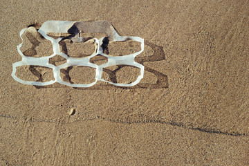 Fototapeta na wymiar plastic rings in the sand of the beach