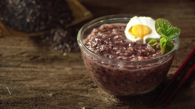Close up of boiled rice berry in bowl on wooden table. Rice berry on background. Food and healthy concept.