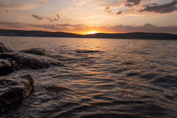 Obraz premium The water at sunset touches the stones 