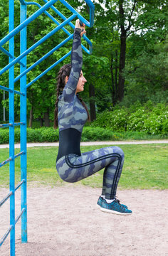 girl hanging on the bar in the Park and trains