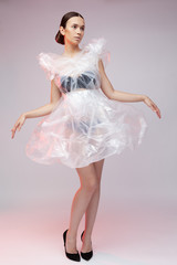 Naklejka premium Girl posing in a dress made of plastic film. Fashion portrait.