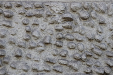 Old grey stone wall with rough blistered texture by inserted round boulders