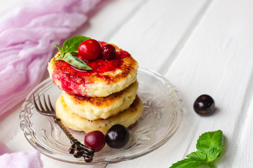 Cottage cheese pancakes on a dark background. Syrniki with fresh mint. Pancakes with cottage cheese on a lilac plate . Homemade food.