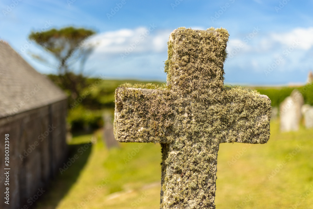 Wall mural an old cross in the south of england in cornwall. the stone cross is overgrown with moss. blue sky, 