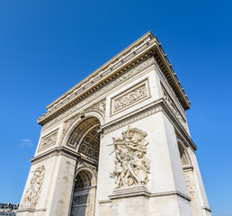 Fototapeta na wymiar Three-quarter view of the eastern facade of the Arc de Triomphe in Paris, France, illuminated by the morning sunlight under a blue sky.