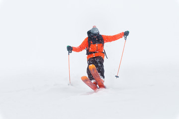 Professional Skier athlete rides out of deep snow while performing a skiing trick in a snowstorm. The winter season is a good powder day. Winter extreme sports